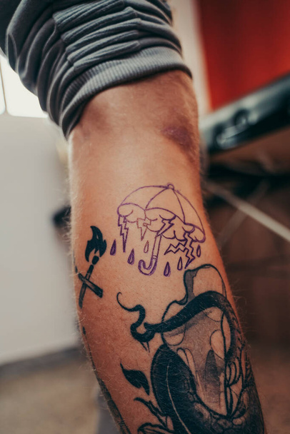 Tetováló művész üzembe egy design egy ügyfél lábát egy tetováló stúdió. - Fotó, kép