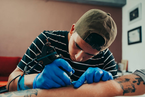 Επαγγελματίας καλλιτέχνης τατουάζ που εργάζεται στο στούντιο τατουάζ του. - Φωτογραφία, εικόνα