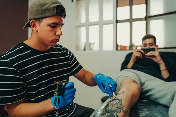 Επαγγελματίας καλλιτέχνης τατουάζ που εργάζεται στο στούντιο τατουάζ του. - Φωτογραφία, εικόνα