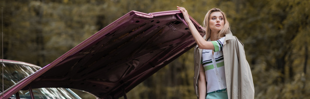 mladá žena dívá pryč při otevírání kapoty rozbité vinobraní auta, prapor - Fotografie, Obrázek