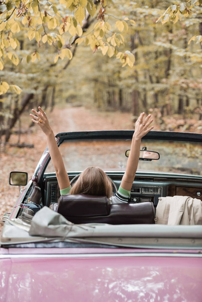 back view of young woman sitting in retro cabriolet in forest - Foto, Bild