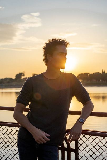 Gölde genç bir adamın portresi Güzel bir günbatımıyla - Fotoğraf, Görsel