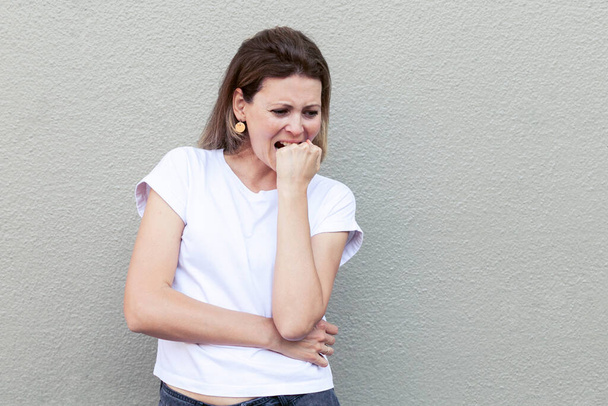 Giovane donna sta vivendo lo stress e le emozioni negative morde il pugno. - Foto, immagini