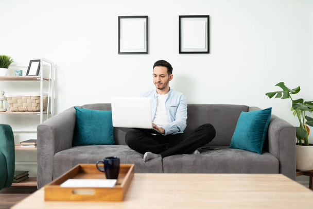 Hezký muž po třicítce dělá domácí kancelář a sedí na gauči v obýváku - Fotografie, Obrázek