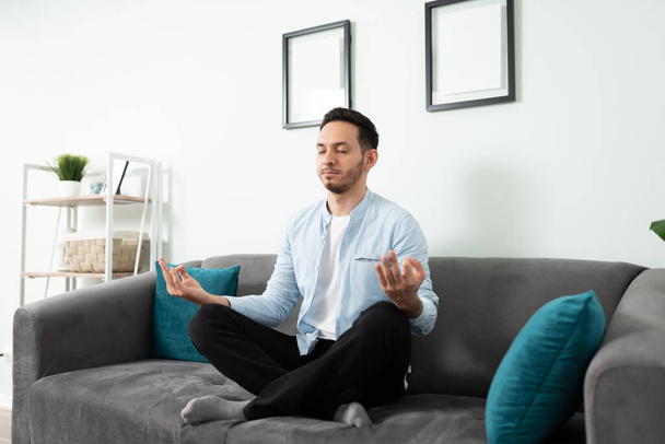 Portret Latynosa po trzydziestce medytującego i spokojnie wyglądającego z zamkniętymi oczami w domu. - Zdjęcie, obraz