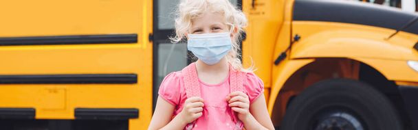 Sarı otobüsün yanında maskeli bir kız. Yüzünde kişisel koruyucu ekipman olan bir çocuk. Eğitim ve Eylül 'de okula dönüş. Koronavirüs sırasında yeni bir normal. Web başlığı. - Fotoğraf, Görsel