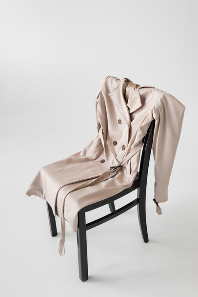 trendy trench coat on chair and white background - Foto, afbeelding