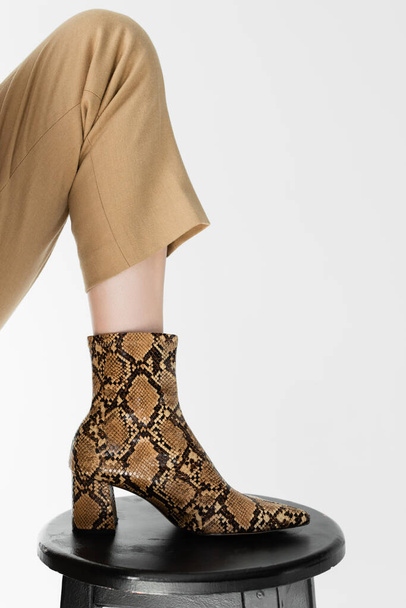 cropped view of female leg in footwear with animal print on stool isolated on white - Φωτογραφία, εικόνα