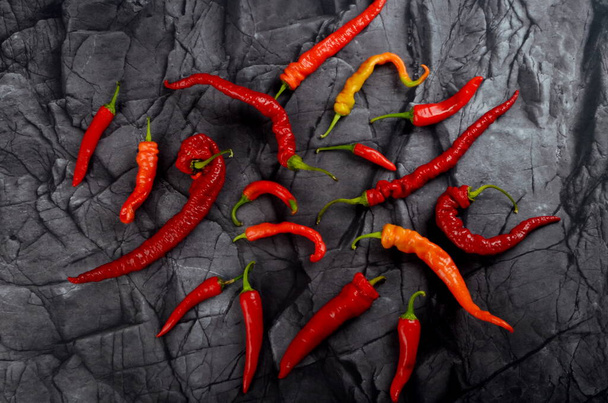 Πολλές κόκκινες καυτερές πιπεριές τσίλι σε φυσικό μαύρο φόντο πέτρα, top view - Φωτογραφία, εικόνα