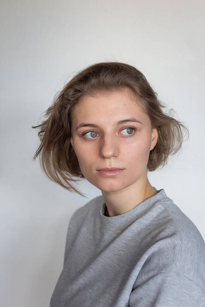 portrait of pretty woman with short hair posing in sweatshirt on white - Photo, Image