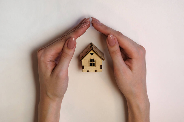 Female hands holding a small miniature wooden cabin. Mortgage insurance, the dream of moving and a real estate concept - Foto, Imagen