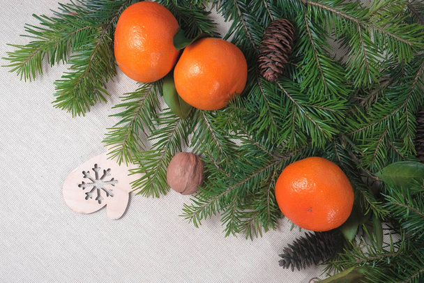 Fir branches, tangerines and handmade Christmas toys and mouse on a light flax background. View from above. Copy space - Foto, Bild