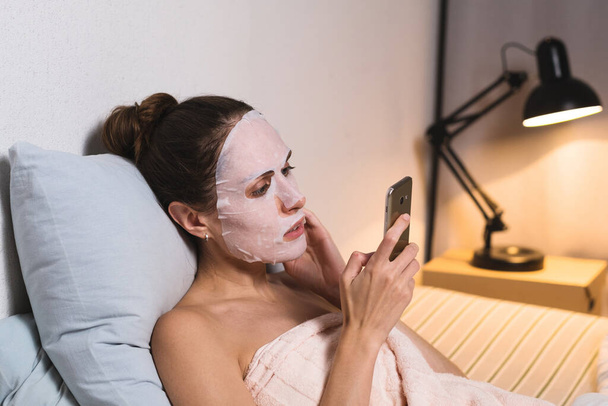 Female skin care cosmetic procedure browse phone. - Photo, Image