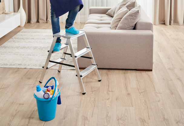 Cropped view of man climbing ladder to clean ceiling. Cleaning service concept - Photo, Image