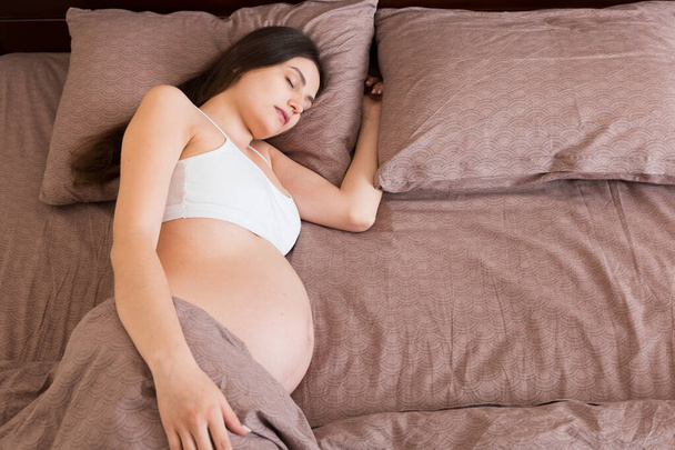 красивая молодая беременная женщина лежит в постели, вид сверху. девушка страдает от того, что ее бросил муж. - Фото, изображение