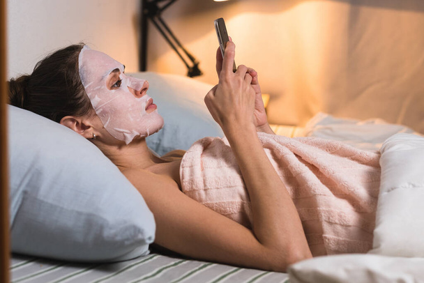 Female skin care cosmetic procedure browse phone. - Foto, Imagen