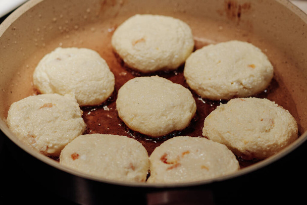 Kookproces van heerlijke gebakken syrniki close-up in de pan. Traditioneel in Oekraïne, Wit-Rusland en Rusland kwark pannenkoeken. Selectieve focus. - Foto, afbeelding