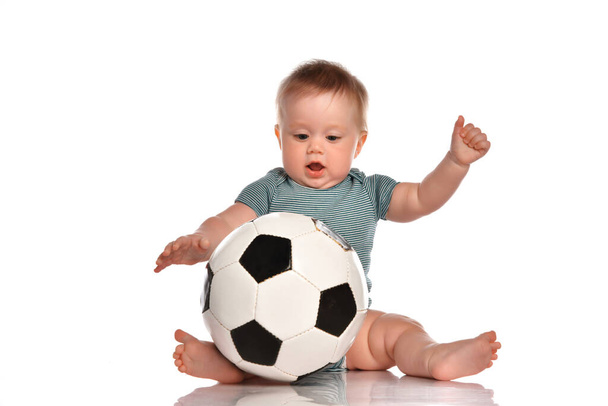 Baby boy sitting and playing a classic soccer ball on a white background. - Fotó, kép