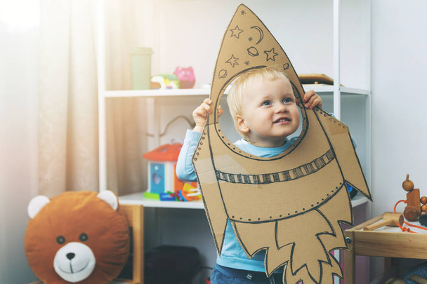 kleiner Junge, der zu Hause mit einem Raumschiff aus Pappe spielt. Fantasie und Traumberuf-Konzept - Foto, Bild