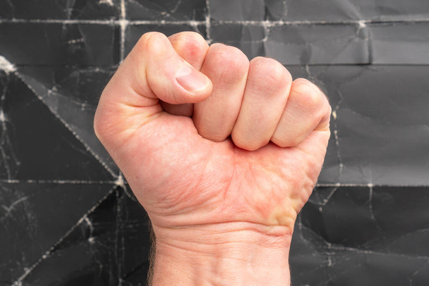 Мужчина сжал кулак на черном фоне гранжа. Концепция свободы и борьбы - Фото, изображение