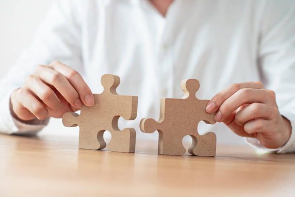 Business solutions partnership and strategy concept, Businessman hand connecting jigsaw puzzle on desk. - Photo, Image