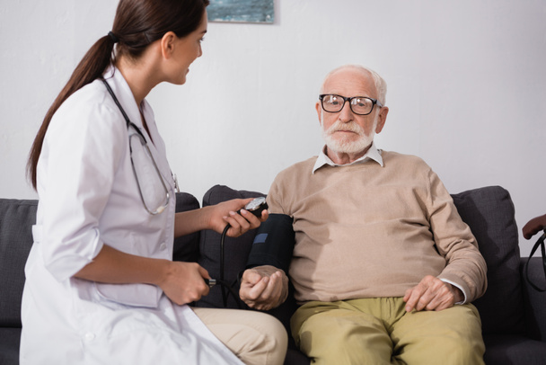 брюнетка геріатрична медсестра вивчає літнього чоловіка зі стетоскопом
 - Фото, зображення