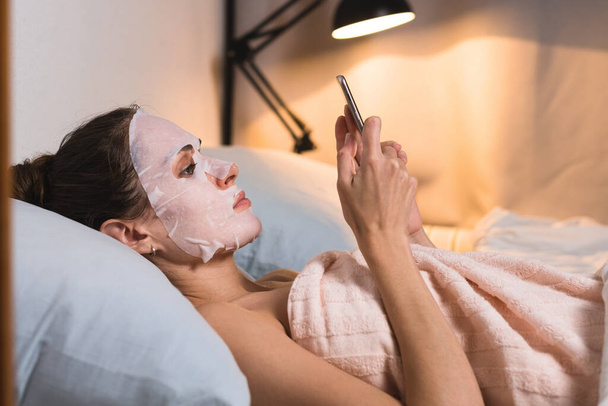 Female skin care cosmetic procedure browse phone. - Foto, imagen