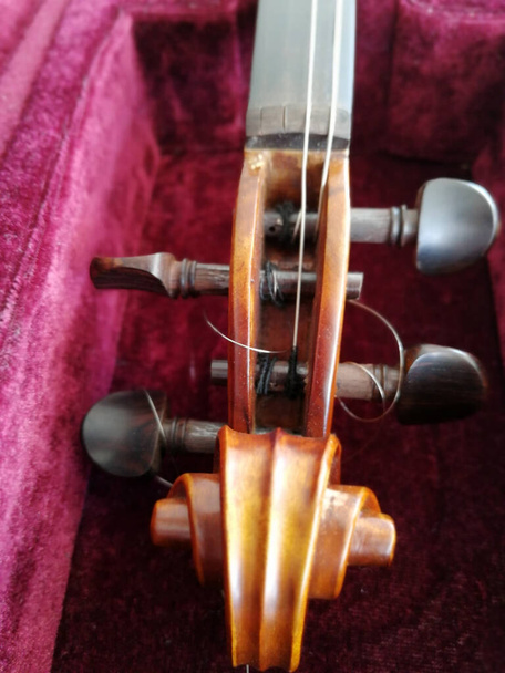 Geige und Bogen in dunkelrotem Etui. Nahaufnahme - Foto, Bild
