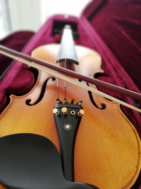 Geige und Bogen in dunkelrotem Etui. Nahaufnahme - Foto, Bild