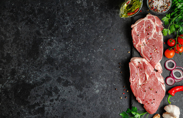 Fresh pork fillet steaks with vegetables and spices on dark background. Top view, copy space - Fotoğraf, Görsel