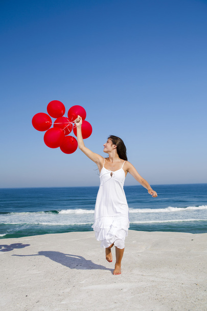 Hermosa chica corriendo con globos rojos
 - Foto, imagen