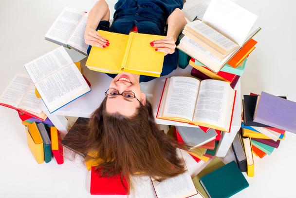 Menina jovem e inteligente deitado com livro cercado por livro colorido
 - Foto, Imagem