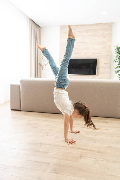 Girl walking upside down on her arms at home - Fotó, kép