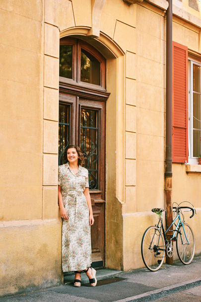 Outdoor portret van jonge mooie vrouw poseren naast de muur, het dragen van maxi jurk - Foto, afbeelding