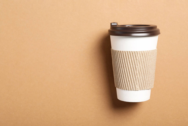 Takeaway paper coffee cup with cardboard sleeve on beige background, top view. Space for text - Photo, Image