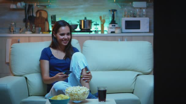 Nainen syö popcornia sohvalla - Materiaali, video