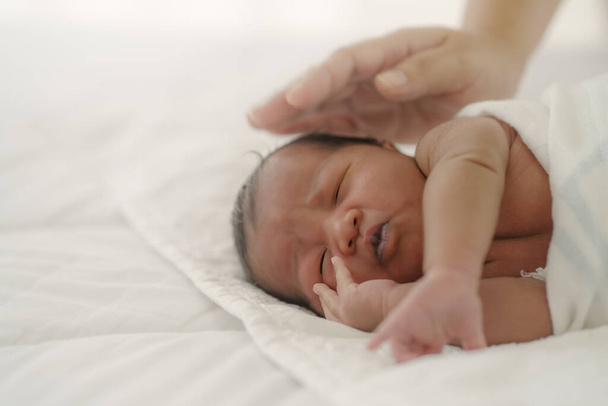 Afrykańskie nowo narodzone dziecko leżące na białym łóżku - Zdjęcie, obraz