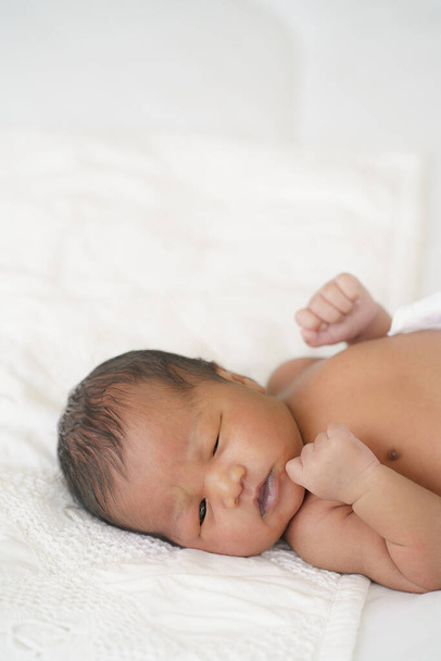 Afrikkalainen amerikkalainen vastasyntynyt vauva makaa valkoisella sängyllä - Valokuva, kuva