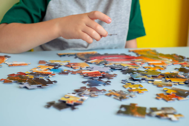 close-up van een kinderhand die een puzzel vasthoudt. Vroegtijdig leren. - Foto, afbeelding