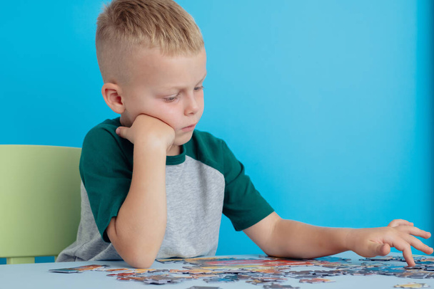 Puzzle game.Focus on the hands of a child holding puzzles.On a yellow background - Photo, Image