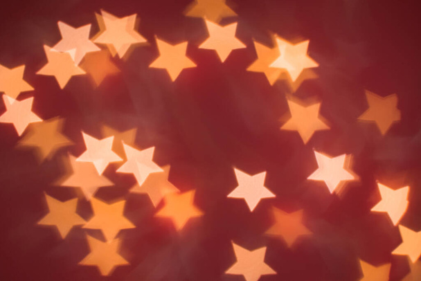 Defocused abstract bokeh lights christmas star shape at red background. orange, gold and red colors. christmas and new year concept - Photo, image