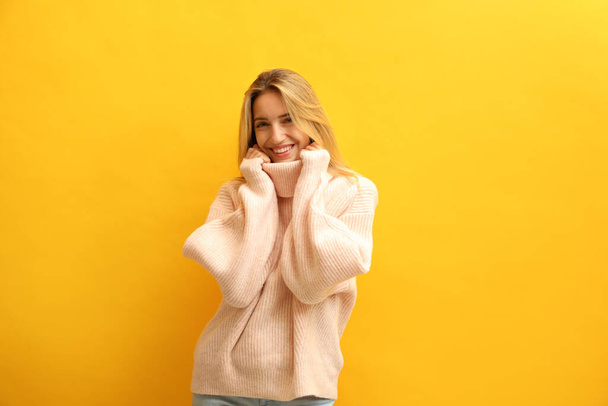 Beautiful young woman wearing knitted sweater on yellow background - Fotoğraf, Görsel
