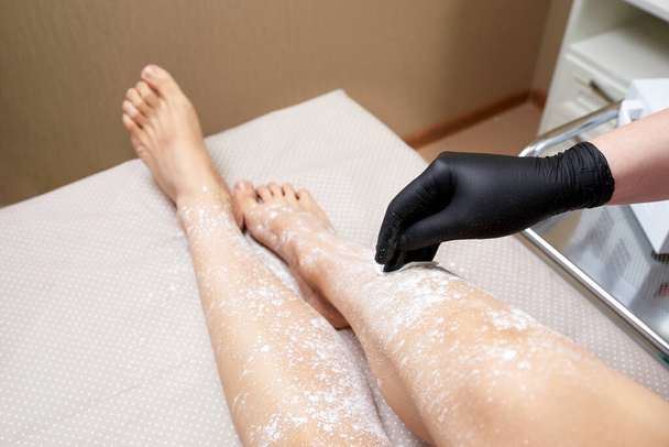 Güzellik uzmanı spa merkezinde kadın bacaklarını ağdalamaya hazırlanıyor. Tüy dökümü için hazırlık, beyaz toz sürüyorum. - Fotoğraf, Görsel