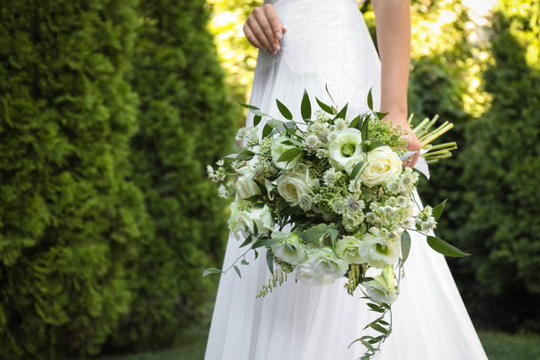 Novia en hermoso vestido de novia con ramo al aire libre, primer plano - Foto, imagen