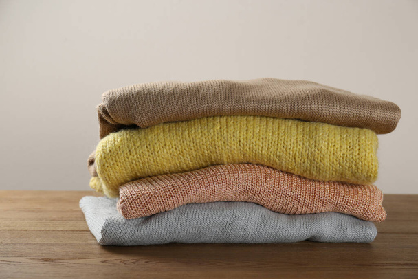Stack of knitted sweaters on wooden table - Fotoğraf, Görsel