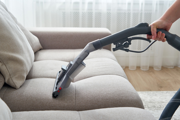 Sofá de limpieza de ama de casa joven con aspiradora en el salón - Foto, Imagen