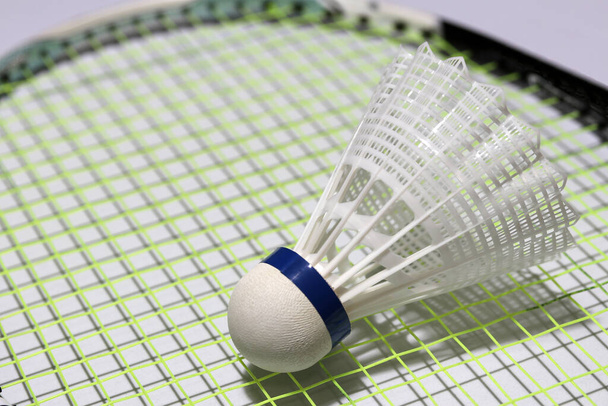 Plastový raketoplán z badmintonu nasadil zelený plastový raketoplán z badmintonu na zelenou síť badmintonové rakety. je to korek, ke kterému jsou připevněna pera, aby vytvořily kuželovitý tvar. - Fotografie, Obrázek