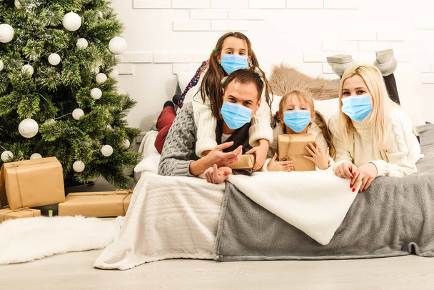 Koruyucu maskeli aile karantinaya alındı. Koronavirüslü normal bir hayat. Yaşam tarzı COVID-19. Karantina Virüsü Koruma Noeli - Fotoğraf, Görsel