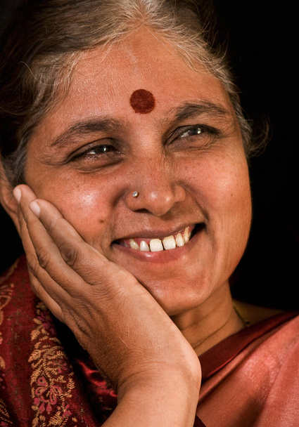 Portrét šťastně se usmívající starší indické ženy na černém pozadí. - Fotografie, Obrázek