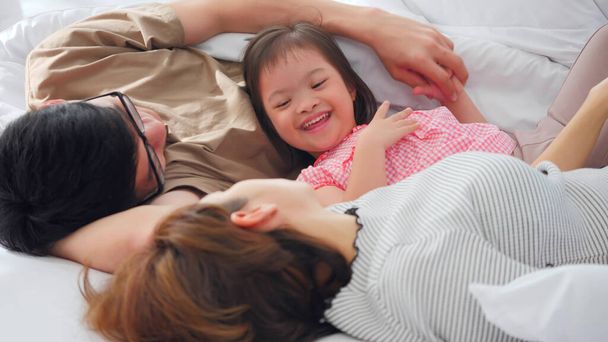 Glückliche Familie mit Mutter, Vater und behinderter Tochter verbringen Zeit miteinander im Schlafzimmer. - Foto, Bild